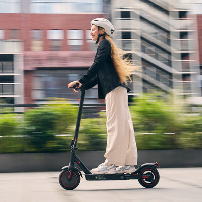 Person riding an electric scooter on a city street with blurred background